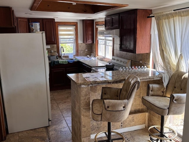 2177 N Merrimac Ave, Chicago, IL 60639 - kitchen with freestanding refrigerator, electric range, a sink, a peninsula, and decorative backsplash
