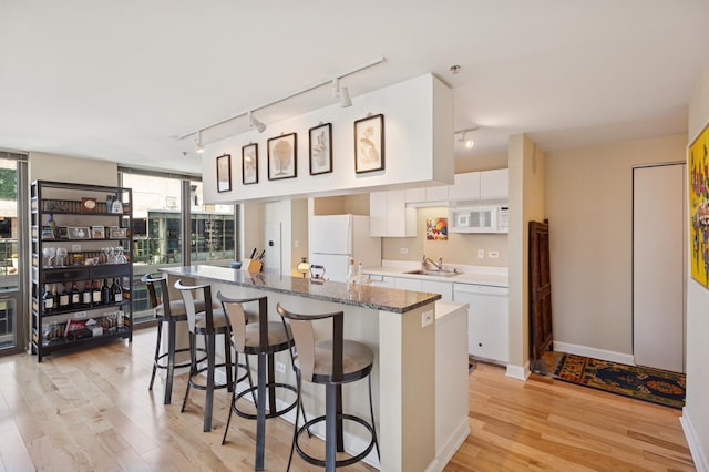 2 E Erie St Unit 2505, Chicago, IL 60611 - kitchen with rail lighting, white appliances, a sink, and light wood finished floors