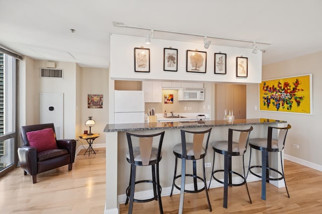 2 E Erie St Unit 2505, Chicago, IL 60611 - kitchen with white appliances, track lighting, a sink, light wood-style floors, and a breakfast bar