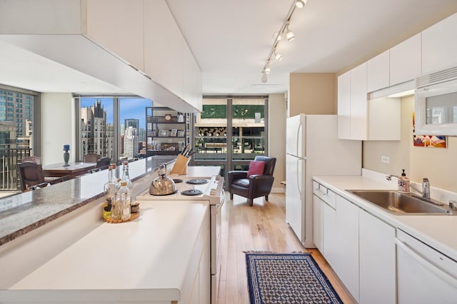 2 E Erie St Unit 2505, Chicago, IL 60611 - kitchen with a sink, white appliances, light wood-type flooring, white cabinets, and a view of skyline
