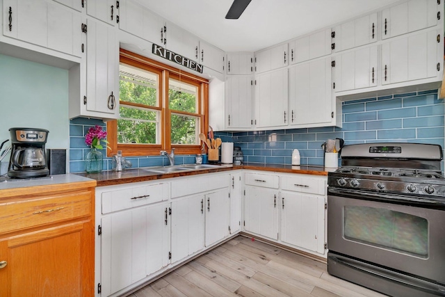 207 Redwood Ave, New Lenox, IL 60451 - kitchen featuring stainless steel range with gas stovetop, a sink, light wood-style floors, tasteful backsplash, and white cabinetry
