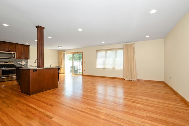 9403 Saratoga Ct, Hickory Hills, IL 60457 - kitchen featuring appliances with stainless steel finishes, light wood finished floors, a kitchen bar, stone countertops, and open floor plan
