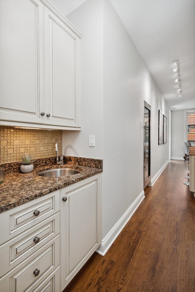 30 W Erie St Unit 402, Chicago, IL 60654 - bar featuring a sink, track lighting, dark wood-type flooring, backsplash, and baseboards