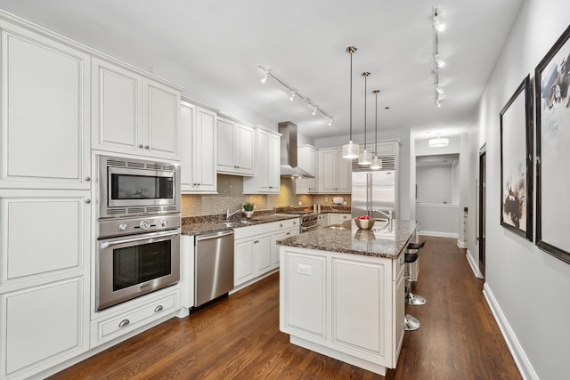 30 W Erie St Unit 402, Chicago, IL 60654 - kitchen with built in appliances, wall chimney exhaust hood, decorative backsplash, white cabinetry, and baseboards
