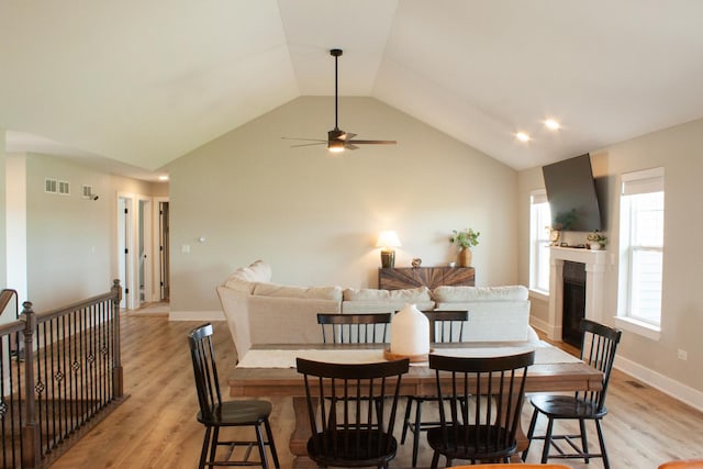 1785 Condor Dr, Manteno, IL 60950 - dining room featuring light wood-style floors, vaulted ceiling, ceiling fan, a glass covered fireplace, and baseboards