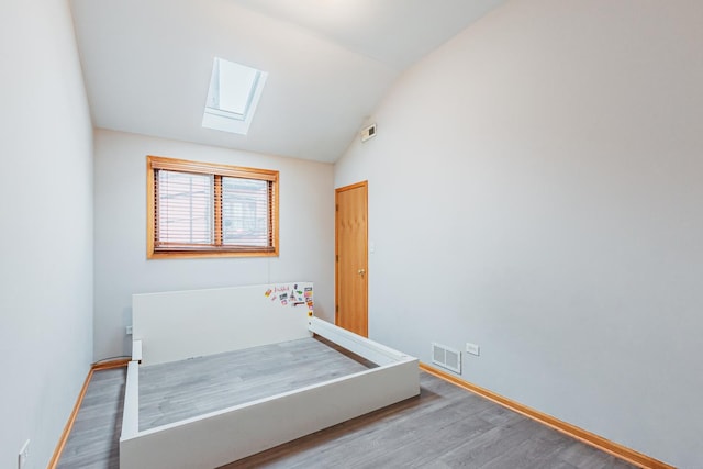 2413 W Taylor St, Chicago, IL 60612 - bedroom featuring a skylight, wood finished floors, vaulted ceiling, and baseboards