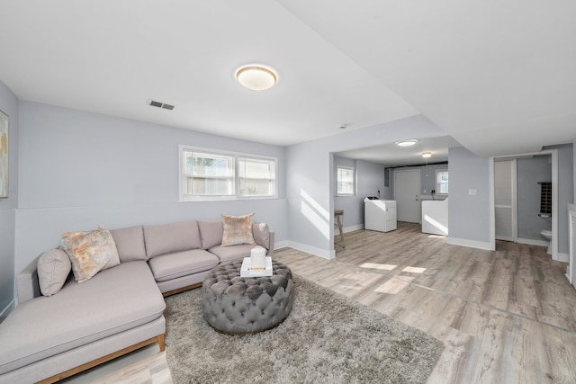473 W Verret St, Elmhurst, IL 60126 - living area featuring light wood-type flooring, plenty of natural light, washing machine and clothes dryer, and baseboards