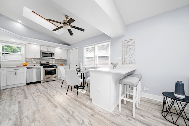 473 W Verret St, Elmhurst, IL 60126 - kitchen featuring stainless steel appliances, vaulted ceiling, light wood-style flooring, a breakfast bar, and backsplash