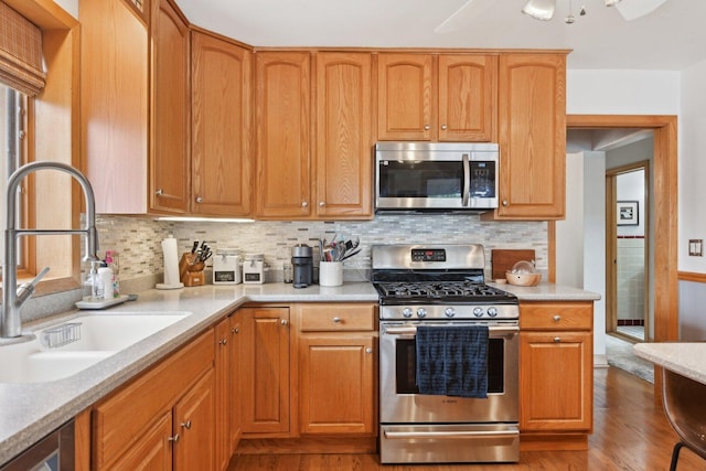 7517 N Oketo Ave, Chicago, IL 60631 - kitchen with appliances with stainless steel finishes, a sink, wood finished floors, light countertops, and decorative backsplash
