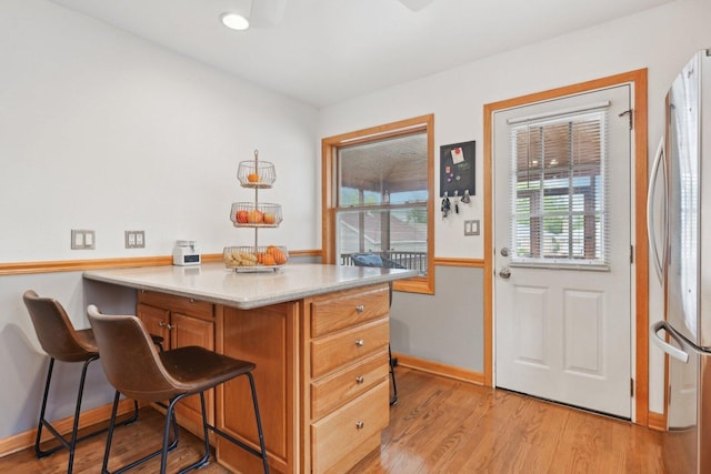 7517 N Oketo Ave, Chicago, IL 60631 - kitchen with freestanding refrigerator, baseboards, light wood finished floors, a breakfast bar area, and a peninsula