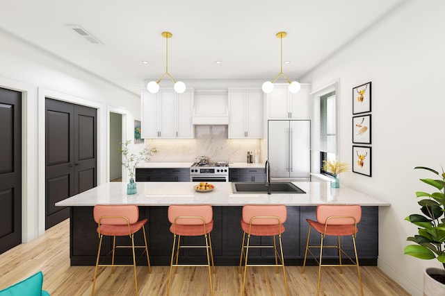 2636 W Evergreen Ave Unit 1, Chicago, IL 60622 - kitchen featuring built in fridge, light wood finished floors, white cabinetry, a breakfast bar, and tasteful backsplash