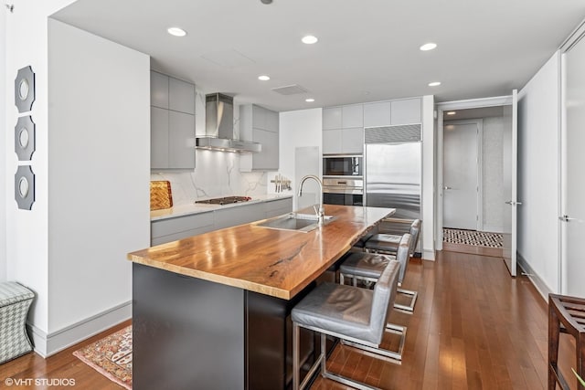 401 N Wabash Ave Unit 54E, Chicago, IL 60611 - kitchen featuring built in appliances, wall chimney range hood, gray cabinetry, a sink, and a kitchen bar