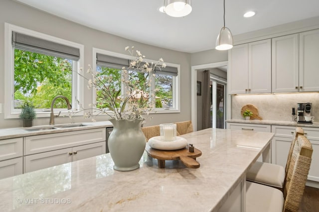 614 S Patton Ave, Arlington Heights, IL 60005 - kitchen featuring a sink, tasteful backsplash, light stone counters, white cabinets, and decorative light fixtures