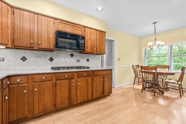 1025 Oxford Rd, Deerfield, IL 60015 - kitchen with black microwave, stainless steel gas stovetop, brown cabinetry, light wood-style flooring, and a chandelier