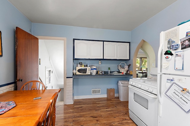 18122 Wentworth Ave, Lansing, IL 60438 - kitchen featuring white appliances, arched walkways, wood finished floors, white cabinets, and dark countertops