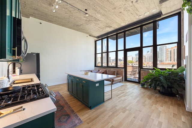 320 E 21st St Unit 402, Chicago, IL 60616 - kitchen featuring green cabinets, light wood-type flooring, appliances with stainless steel finishes, a sink, and baseboards