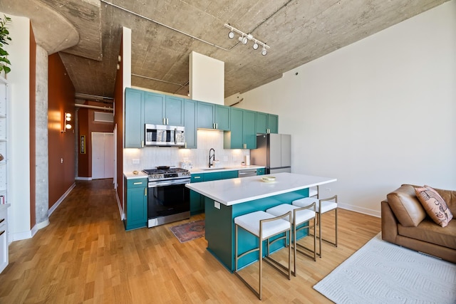 320 E 21st St Unit 402, Chicago, IL 60616 - kitchen with stainless steel appliances, a breakfast bar, blue cabinetry, light wood-style floors, and backsplash
