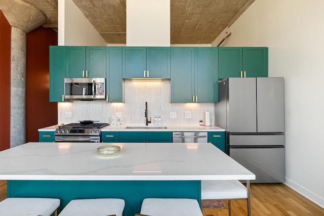 320 E 21st St Unit 402, Chicago, IL 60616 - kitchen featuring appliances with stainless steel finishes, a sink, light wood-style flooring, a kitchen breakfast bar, and decorative backsplash