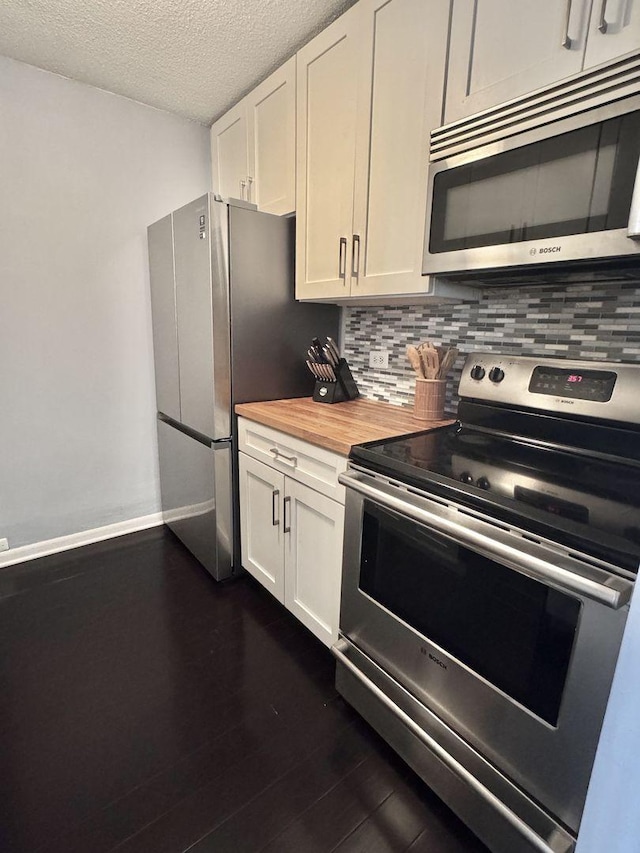 2740 N Pine Grove Ave Unit 9B, Chicago, IL 60614 - kitchen with appliances with stainless steel finishes, decorative backsplash, wooden counters, white cabinetry, and a textured ceiling