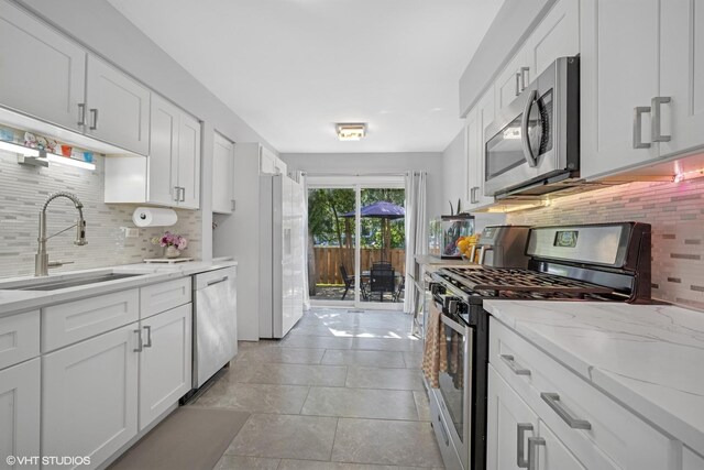 603 Barberry Ln, Wheeling, IL 60090 - kitchen featuring appliances with stainless steel finishes, a sink, decorative backsplash, white cabinetry, and light stone counters