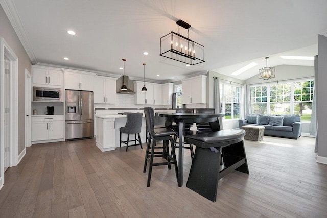 6704 Whisper Glen Dr, Plainfield, IL 60586 - kitchen with appliances with stainless steel finishes, wall chimney exhaust hood, wood finished floors, a chandelier, and white cabinets