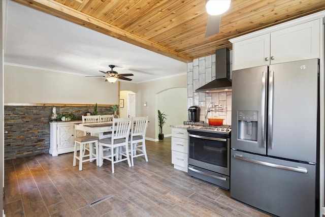 404 Vale Ave N, Rockford, IL 61107 - kitchen with stainless steel appliances, wall chimney range hood, a ceiling fan, white cabinetry, and arched walkways