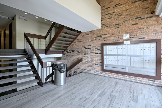 1806 Hemlock Pl Unit 105, Schaumburg, IL 60173 - stairs with brick wall, mail area, a high ceiling, and wood finished floors