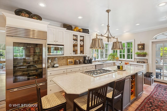 539 N E Ave, Oak Park, IL 60302 - kitchen featuring stainless steel appliances, decorative backsplash, a kitchen breakfast bar, glass insert cabinets, and white cabinetry