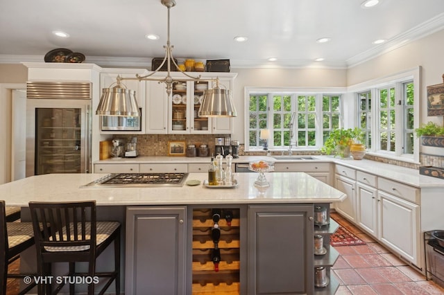 539 N E Ave, Oak Park, IL 60302 - kitchen with stainless steel gas cooktop, backsplash, healthy amount of natural light, a breakfast bar, and crown molding