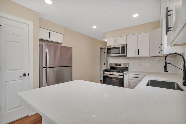 18024 Birch Ave, Country Club Hills, IL 60478 - kitchen featuring stainless steel appliances, a sink, backsplash, white cabinetry, and a peninsula