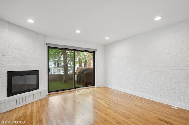 3759 N Kenmore Ave Unit A, Chicago, IL 60613 - unfurnished living room with baseboards, wood finished floors, recessed lighting, a glass covered fireplace, and brick wall