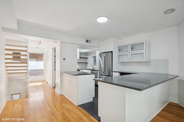 3759 N Kenmore Ave Unit A, Chicago, IL 60613 - kitchen with a peninsula, freestanding refrigerator, dark countertops, light wood-style floors, and white cabinets