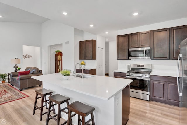 8716 Pebble Creek Ct, Wonder Lake, IL 60097 - kitchen with stainless steel appliances, a sink, light wood finished floors, a kitchen bar, and light countertops