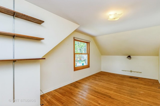 additional living space featuring wood finished floors, baseboards, and lofted ceiling