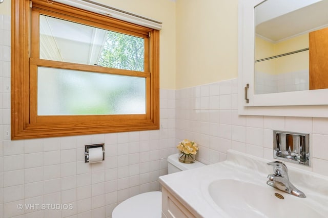 bathroom with toilet, vanity, and tile walls