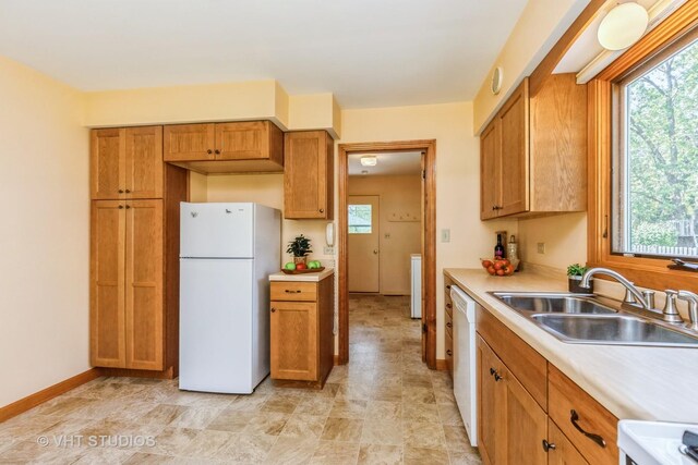 kitchen featuring white appliances, a sink, light countertops, and healthy amount of natural light