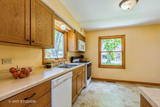 kitchen featuring white appliances, a sink, plenty of natural light, and light countertops