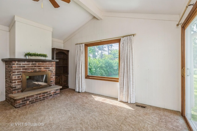 unfurnished living room featuring ceiling fan, plenty of natural light, carpet flooring, a brick fireplace, and wood walls