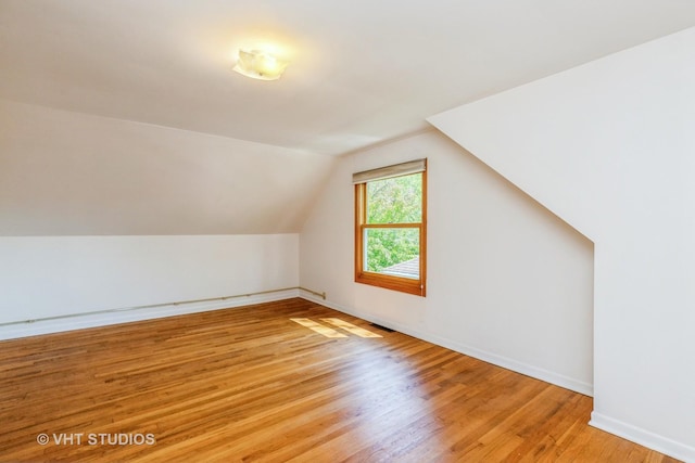 additional living space with light wood-type flooring, baseboards, and lofted ceiling