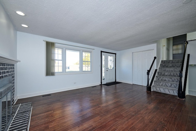 1613 Hartmann Dr, Schaumburg, IL 60193 - unfurnished living room with wood finished floors, a textured ceiling, stairs, a brick fireplace, and baseboards