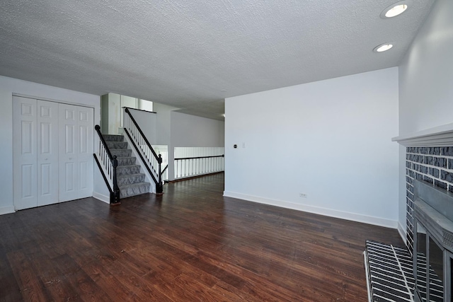 1613 Hartmann Dr, Schaumburg, IL 60193 - unfurnished living room with a fireplace, wood finished floors, baseboards, a textured ceiling, and stairs