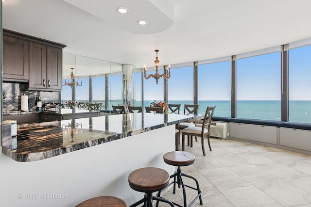 505 N Lake Shore Dr Unit 4807, Chicago, IL 60611 - kitchen with a chandelier, dark brown cabinetry, a water view, dark stone countertops, and a breakfast bar area