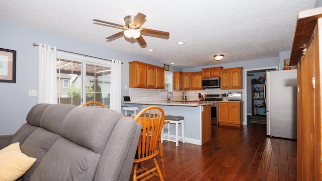 302 Gambel Ct, Normal, IL 61761 - kitchen featuring appliances with stainless steel finishes, a peninsula, dark wood-type flooring, tasteful backsplash, and ceiling fan