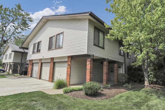 view of side of property with brick siding, an attached garage, driveway, and a yard