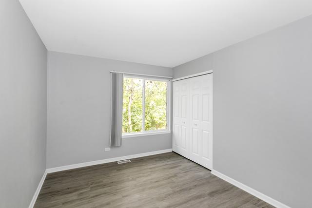 unfurnished bedroom featuring baseboards, wood finished floors, and a closet