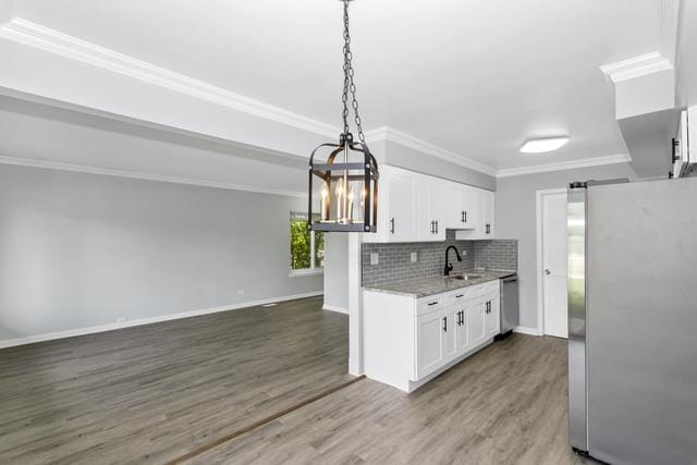 kitchen with appliances with stainless steel finishes, a sink, white cabinets, crown molding, and a chandelier