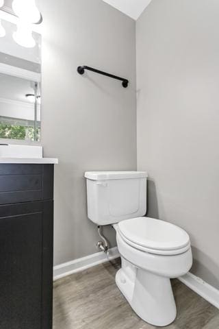 bathroom featuring wood finished floors, toilet, baseboards, and vanity