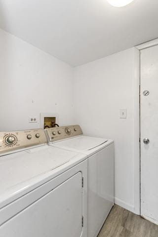 laundry area with washing machine and clothes dryer and light wood finished floors