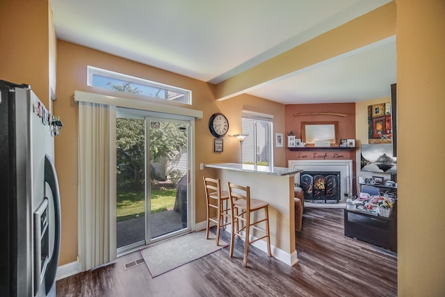 1163 Whispering Hills Dr, Naperville, IL 60540 - kitchen featuring stainless steel fridge, baseboards, dark wood-style floors, a warm lit fireplace, and a breakfast bar