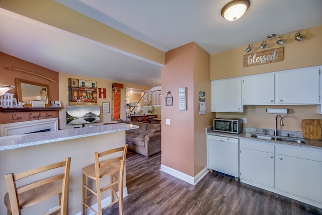 1163 Whispering Hills Dr, Naperville, IL 60540 - kitchen with white dishwasher, a sink, dark wood-type flooring, baseboards, and a kitchen breakfast bar